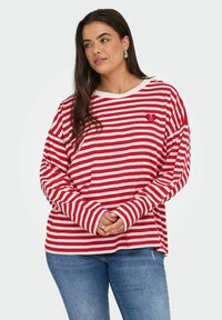 Maglietta a maniche lunghe a righe rosse e bianche con una vestibilità rilassata, scollatura rotonda e un piccolo logo a forma di cuore sul petto sinistro. Design casual.