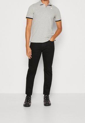 Polo gris avec des rayures d'accent jaunes et bleu marine sur les manches, associé à un pantalon noir et des chaussures de sport noires. Design et coupe simples.