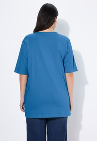 Blue short-sleeve t-shirt with a round neckline, made of soft material, featuring a loose fit and extending to the hip.