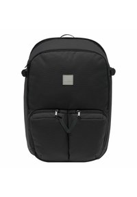 Zaino in nylon nero con forma arrotondata, dotato di due tasche anteriori con zip, una patch con logo e spallacci regolabili. Texture liscia, design minimalista.