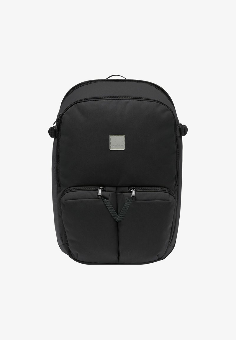 Zaino in nylon nero con forma arrotondata, dotato di due tasche anteriori con zip, una patch con logo e spallacci regolabili. Texture liscia, design minimalista.