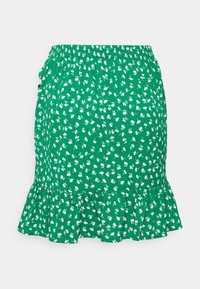 Jupe verte à motifs floraux avec une taille froncée, présentant un ourlet à volants et un petit motif de fleurs blanches. Confectionnée dans un tissu léger.