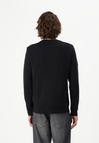 Zwarte crewneck sweatshirt gemaakt van een zachte katoenmix. Heeft lange mouwen en een relaxte pasvorm met ribgebreide manchetten en zoom.