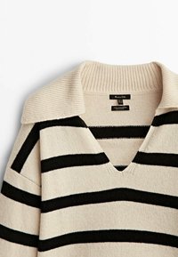 Beige en zwart gestreepte trui gemaakt van wol en kasjmier, met een V-hals en een geribde kraag, met een zachte textuur en gebreid patroon.