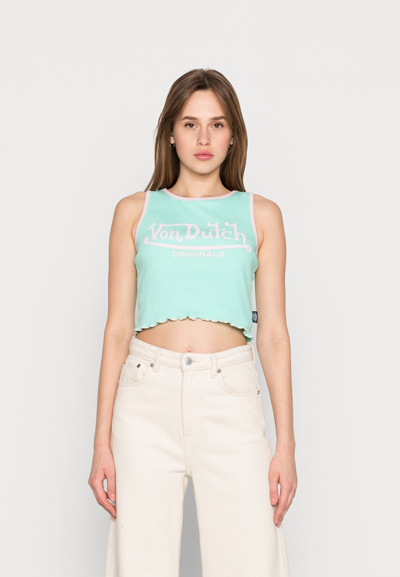 Top cropped verde menta com bainha ondulada, apresentando o texto branco "Von Dutch ORIGINALS". Usado com jeans off-white de cintura alta.