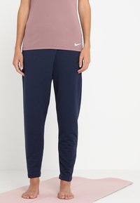 Pantalons de sport bleu marine avec une taille élastique et des jambes fuselées, associés à un haut ajusté rose clair arborant un logo blanc.