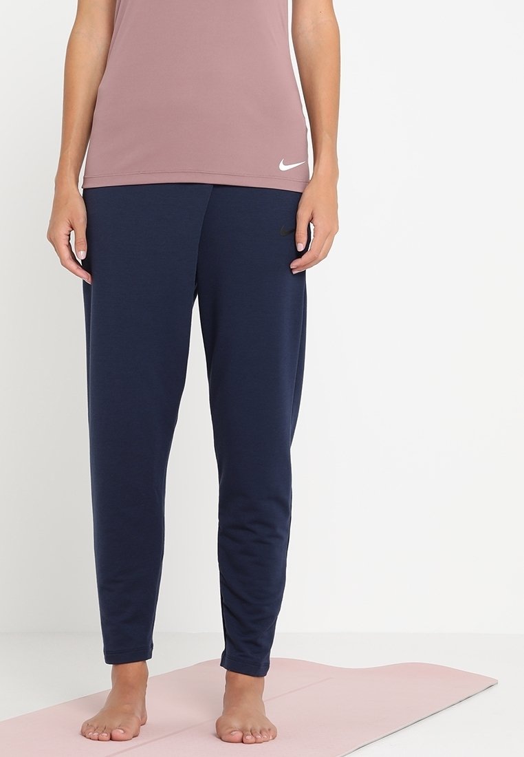 Pantalons de sport bleu marine avec une taille élastique et des jambes fuselées, associés à un haut ajusté rose clair arborant un logo blanc.