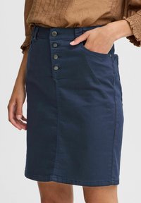 Marinblå denimkjol med en figursydd passform, som har framknäppning, sidofickor och en slät textur.