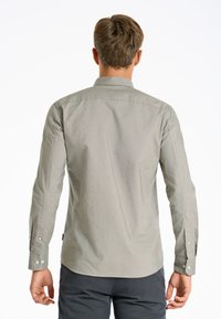 Camicia grigia a maniche lunghe realizzata in tessuto leggero, con colletto a bottoni e polsini abbottonati, caratterizzata da una texture liscia e una leggera lucentezza.