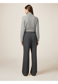 Suéter de cuello alto gris con puños acanalados combinado con pantalones de pierna ancha de cintura alta en un tejido gris oscuro. Diseño simple con líneas limpias.