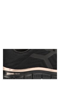 Zapatilla deportiva negra con parte superior de tejido texturizado, suela en un tono nude claro y la marca "HYPERLIGHT" en el lateral. Presenta un diseño minimalista.