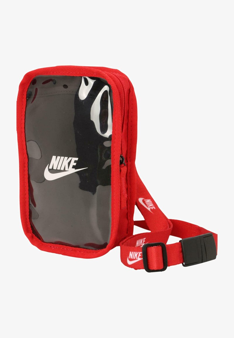 Červená crossbody taška z látky s priehľadným predným panelom, na ktorom je čierne logo Nike a nastaviteľný popruh so zopakovanými akcentmi loga.