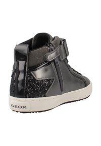Zapatillas altas negras con parte superior de charol, un acento de estrella negra brillante, correa de velcro y suela texturizada.