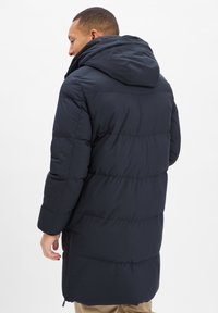 Granatowa puchowa kurtka z kapturem, prążkowaną fakturą i poziomym przeszyciem, z zapinaną na zamek kieszenią boczną i luźnym krojem.