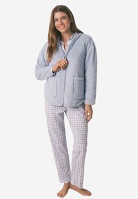 Hellblauer, flauschiger Reißverschluss-Pullover mit zwei Taschen, kombiniert mit karierten Pyjamahosen in Weiß und Blau. Weiche Textur, lässiges Design.