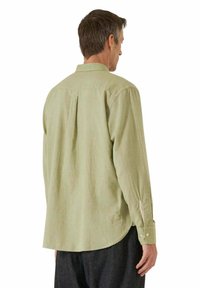 Camicia a maniche lunghe verde chiaro con piega sul rinforzo posteriore, polsini con bottoni e orlo curvo. Realizzata in tessuto morbido con una finitura leggermente strutturata.