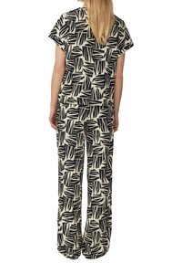 Zwart met crèmekleurige top met bladerenpatroon en wijduitlopende broek van lichte stof, met korte mouwen en een relaxed fit.