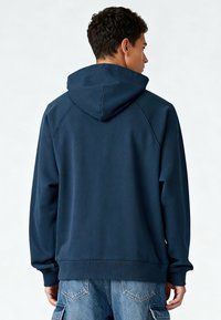 Sweat-shirt à capuche bleu marine, de coupe décontractée, avec poignets et ourlet côtelés, fabriqué dans un tissu texturé pour le confort.