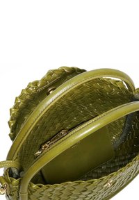 Round handbag in olive green leather with braided accents, featuring a textured woven design and a smooth interior pocket with a zipper.