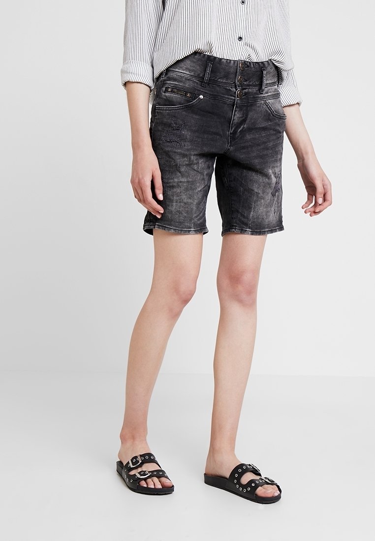 Svarta denimshorts med blekt mönster, midjehöjd och fem fickor. Matchas med en randig långärmad skjorta och svarta sandaler.