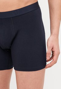 Marineblaue Baumwollunterhosen mit elastischem Bund und GAP-Logo. Glatte Textur, enganliegendes Design und kurze Beinlänge.