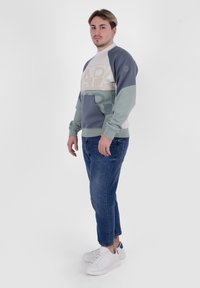 Felpa leggera a blocchi di colore in grigio, beige e teal, con un design grafico sulla parte anteriore, dal taglio rilassato e con polsini a coste.