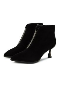Botas tobilleras de ante negro con punta afilada, cremallera lateral y acentos metálicos decorativos, con un tacón medio esculpido.
