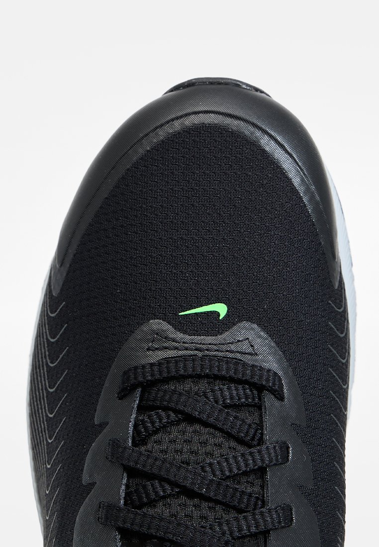 Schwarzer Sportschuh mit textilem Obermaterial, strukturiertem Oberflächen, schwarzen Schnürsenkeln und grünem Nike-Swoosh-Logo. Verfügt über eine verstärkte Zehenkappe.