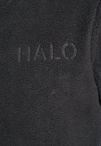 Tissu polaire noir avec une texture subtile, comportant le mot "HALO" en relief dans une section lisse, ajoutant un détail distinctif.