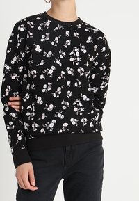 Černá květinová mikina s kombinací růžových a bílých květin, žebrovanými manžetami a lemem, s klasickým designem výstřihu do kulata.