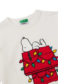 Biała bawełniana koszulka z nadrukiem Snoopy'ego na czerwonej budzie udekorowanej kolorowymi świątecznymi światełkami.