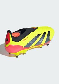 Chaussures de foot Adidas Predator en jaune vif et noir, avec une tige texturée, un design épuré et des accents roses au niveau du talon avec des crampons noirs.