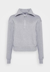 Felpa grigia in pile con colletto alto e chiusura con zip argentata. Presenta polsini e orlo a costine, offrendo una vestibilità rilassata. Design semplice.