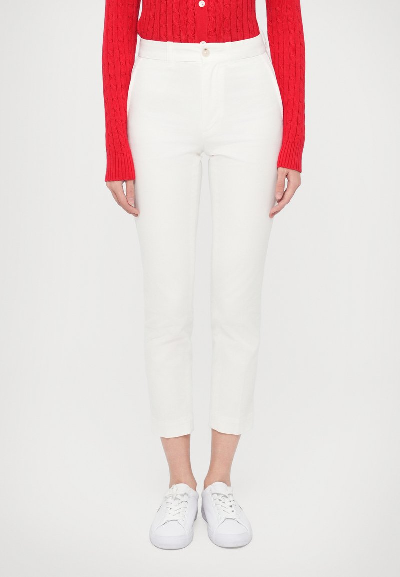 Λευκό παντελόνι cropped με εφαρμοστή γραμμή, διαθέτει κλείσιμο με κουμπί και πλαϊνές τσέπες. Συνδυασμένο με κόκκινο πουλόβερ πλεκτό με σχέδιο καλώδιο και λευκά αθλητικά παπούτσια.