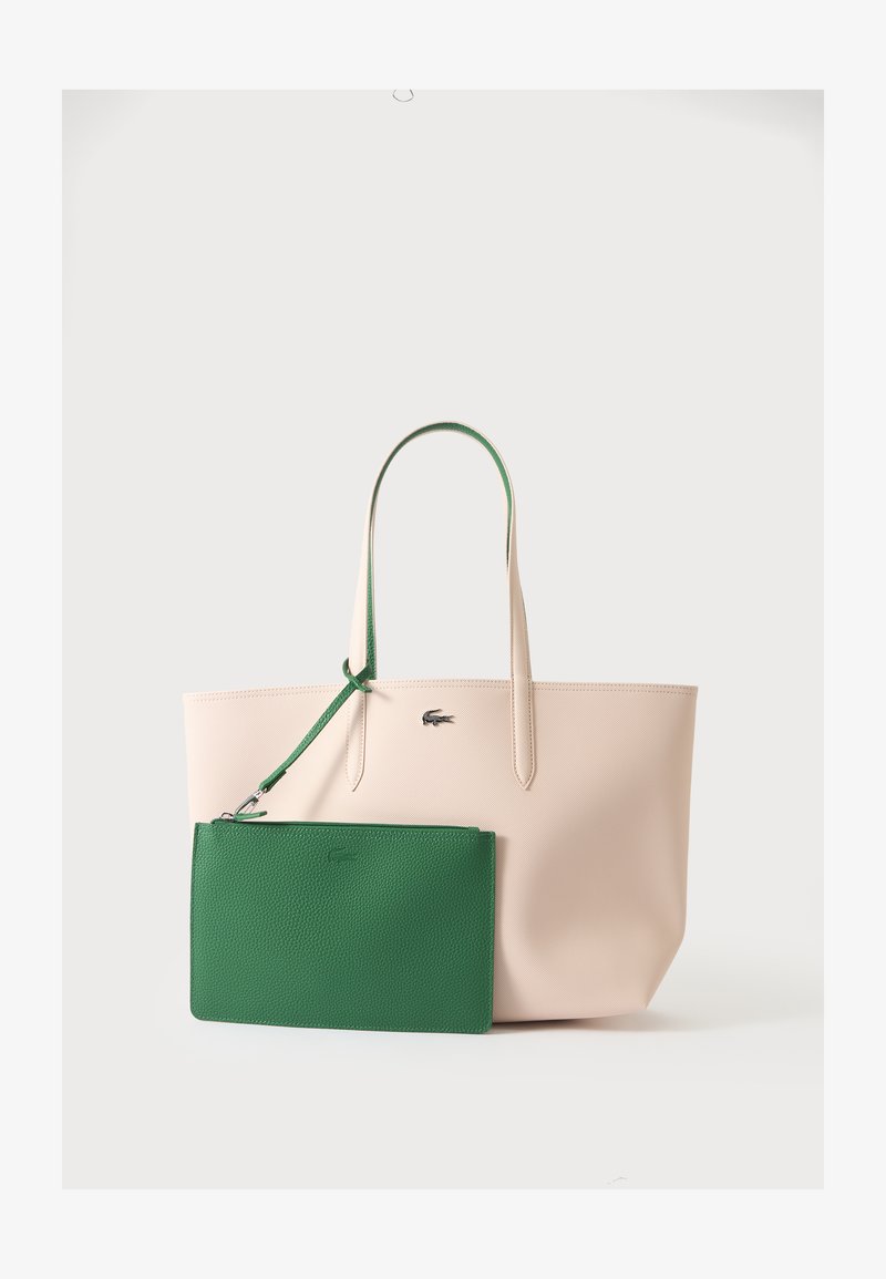 Sac fourre-tout beige avec longues anses et petite pochette zippée verte détachable attachée à une anse, présenté sur un fond uni.