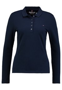 Marinblå långärmad polo med krage och femknäppningsslå. Har en liten logotyp på vänster bröst och en slät yta.