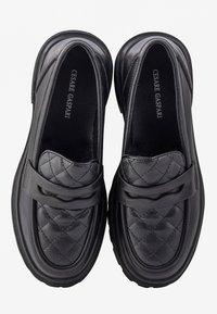 Paire de mocassins en cuir noir avec motif matelassé et détail de sangle, marque "Cesare Gaspari" sur les semelles intérieures, vue de dessus.