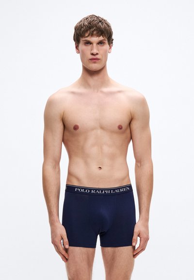 Boxeri bleumarin cu textură moale, prevăzuți cu o talie elastică branduită albă, cu o potrivire strânsă, concepuți pentru confort și susținere.