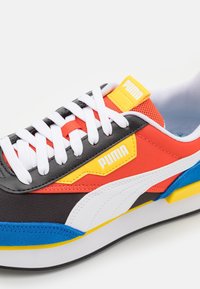 Die PUMA-Sneaker verfügen über ein mehrfarbiges Design mit roten, schwarzen, gelben und blauen Akzenten. Sie bestehen aus strukturierten Materialien, haben weiße Schnürsenkel und Markenzeichen.