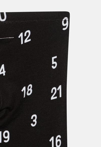 Svart leggings med spredte hvite tall fra 0 til 21, laget av et glatt, stretchy stoff.