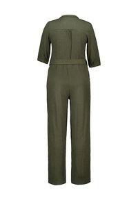 Combinaison vert olive avec des manches trois-quarts, une ceinture à la taille et une coupe décontractée. Tissu texturé avec un détail de bouton sur les manches.