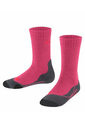 Calcetines rosas con puño acanalado, suela gris acolchada y puntera reforzada. Presenta un logo en naranja brillante y elementos de diseño en contraste.