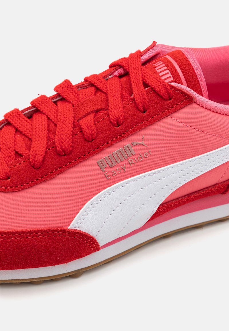 Les baskets Puma Easy Rider rouges et roses présentent une tige en tissu et en daim, une bande latérale blanche et une semelle en caoutchouc texturé avec des coutures détaillées.