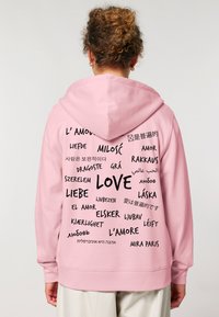 Felpa con cappuccio rosa con testo nero in diverse lingue, con la parola "AMORE" ben in evidenza al centro.