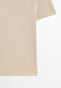 Beige gebreide top met korte mouwen en een gestructureerde afwerking, met een rechte zoom en ribbelmanchetten. De stof lijkt lichtgewicht en ademend te zijn.