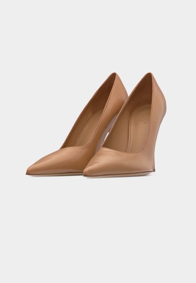 Paire de chaussures à talons aiguilles beige à bout pointu, avec une texture en cuir lisse, présentée sur un fond clair uni.