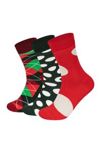 Tre paia di calze: una con un motivo argyle rosso e verde, una con pois bianchi su verde e una rossa solida con un accento di pois bianchi.