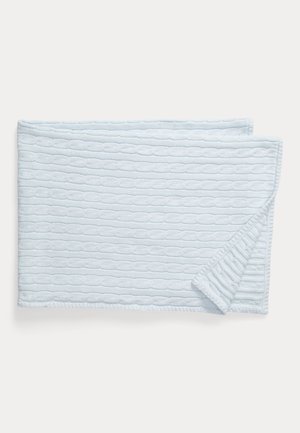 Couverture tricotée bleu clair avec un coin plié montrant un motif torsadé et une bordure côtelée sur fond blanc.