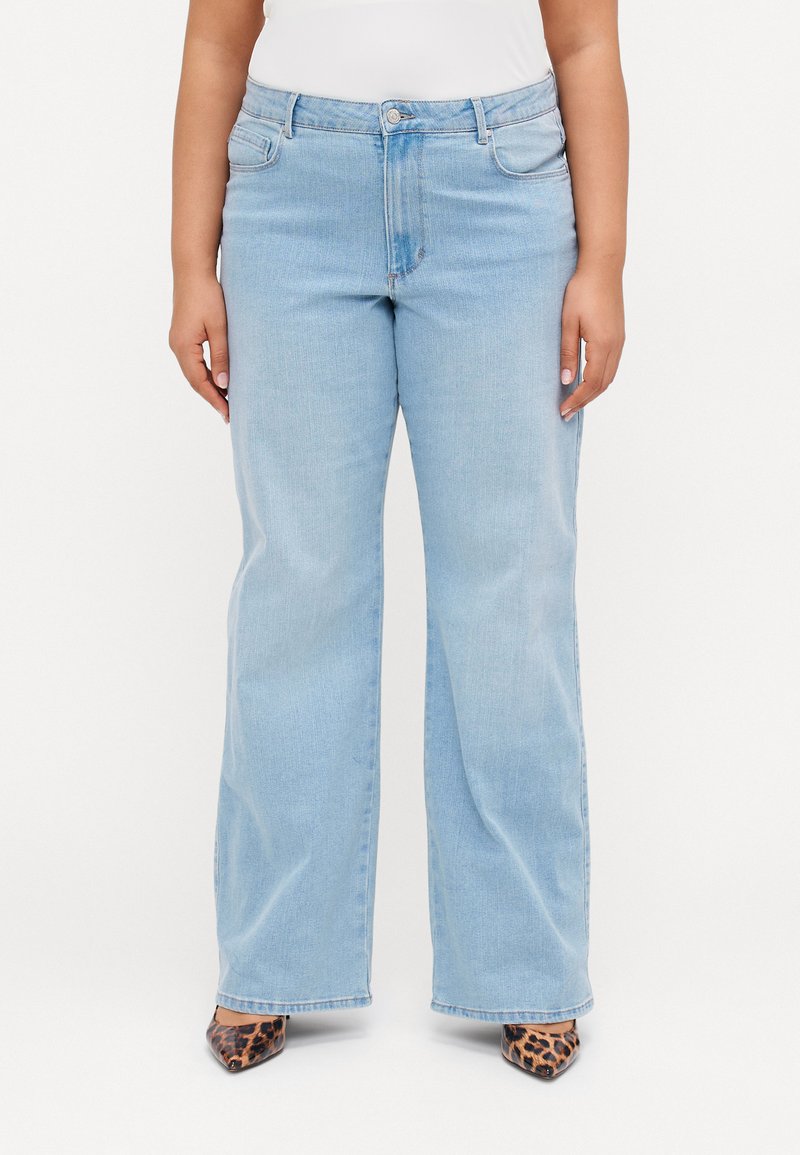 Jeans de perna reta em azul claro, feitos de denim, com bolsos frontais, fecho com botão e um desbotado sutil. Usados com saltos agulha de estampa de leopardo.