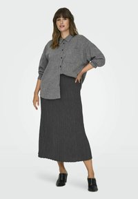 Camicia grigia con bottoni, dalla vestibilità comoda e maniche lunghe, abbinata a una gonna maxi a coste scura e mule con tacco neri.